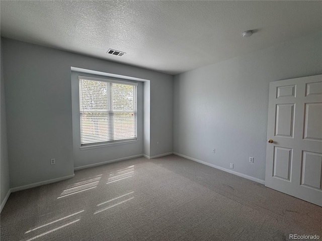 spare room featuring baseboards, carpet, a textured ceiling, and visible vents