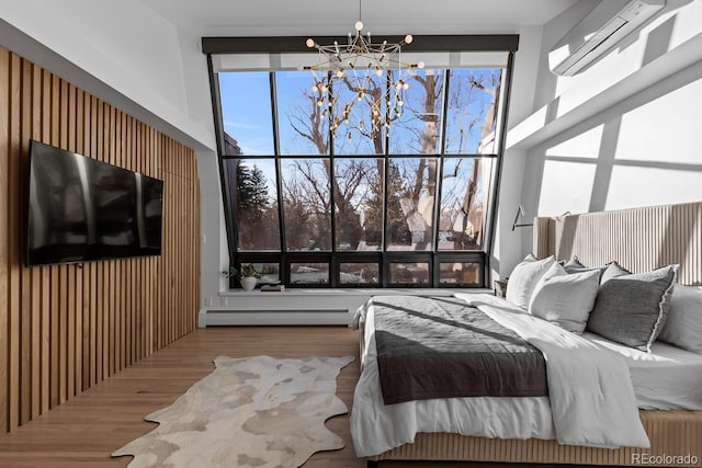 bedroom with a wall unit AC, wood finished floors, a high ceiling, a baseboard heating unit, and a notable chandelier