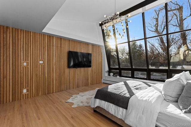 bedroom featuring expansive windows, wooden walls, and wood finished floors