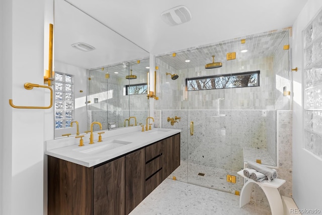 bathroom featuring a shower stall, double vanity, visible vents, and a sink