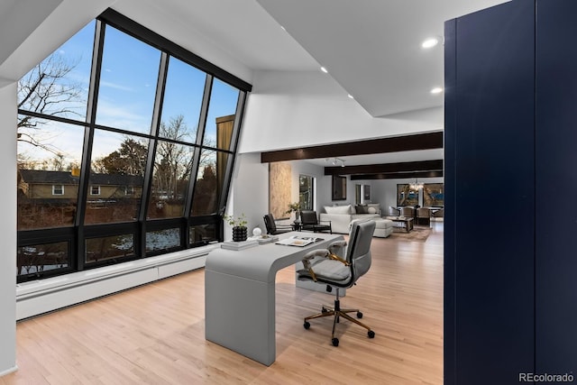 home office with recessed lighting, baseboard heating, wood finished floors, and a towering ceiling