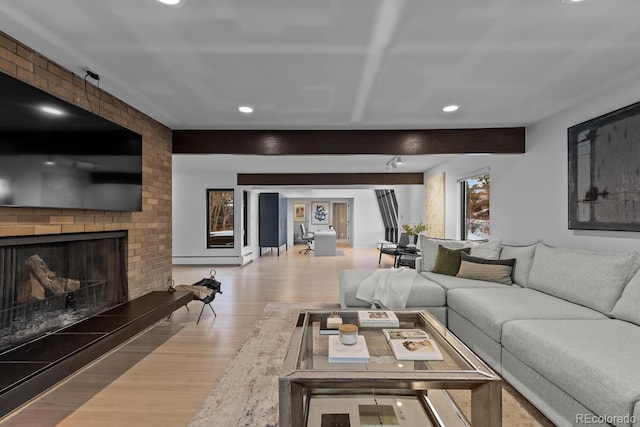 living area featuring beam ceiling, a brick fireplace, recessed lighting, and wood finished floors