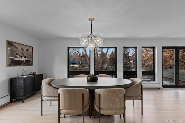 dining area featuring light wood-style flooring, baseboard heating, a wealth of natural light, and a chandelier