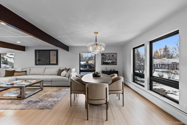 dining space with beamed ceiling, baseboard heating, an inviting chandelier, and light wood-style flooring