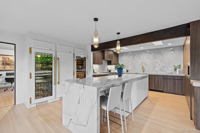 kitchen with light wood-type flooring, beam ceiling, modern cabinets, tasteful backsplash, and a center island