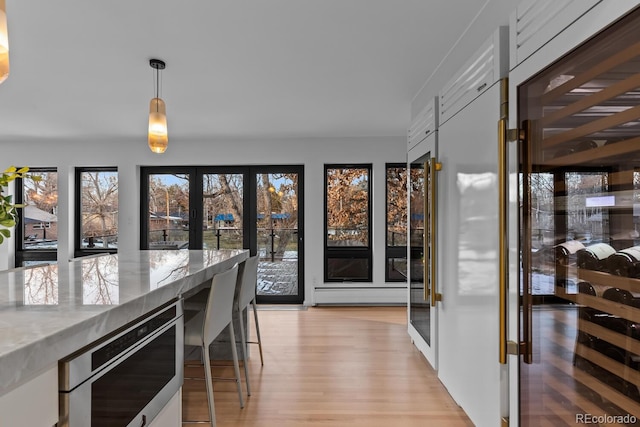 dining space featuring beverage cooler, light wood-type flooring, and french doors