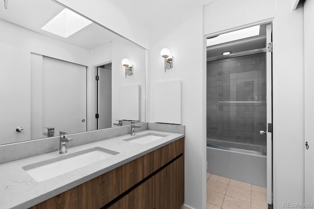 full bath with double vanity, a skylight, bath / shower combo with glass door, and a sink