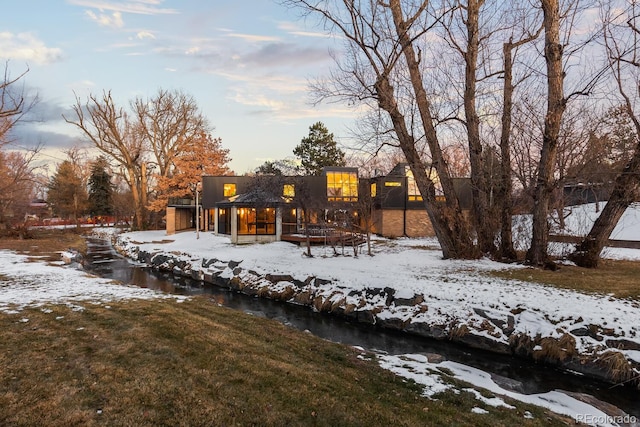 snow covered back of property featuring a lawn