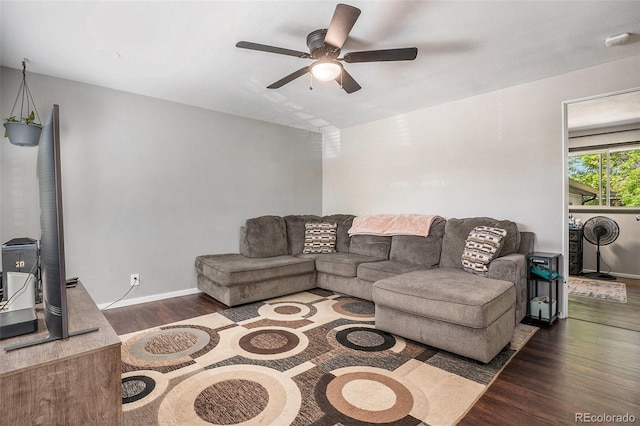 living area with a ceiling fan, wood finished floors, and a wood stove