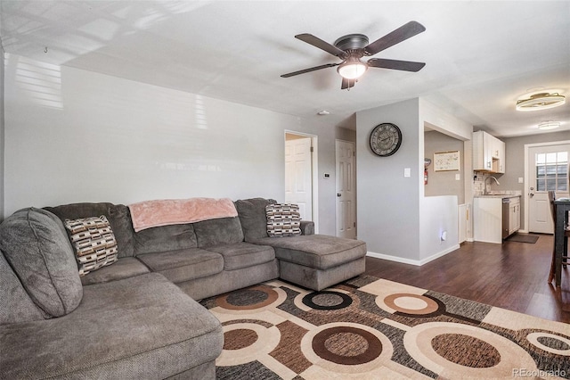 living room with dark wood-type flooring, ceiling fan, and baseboards