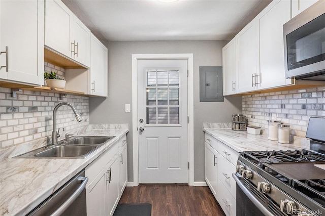 kitchen featuring stainless steel appliances, a sink, electric panel, dark wood finished floors, and decorative backsplash