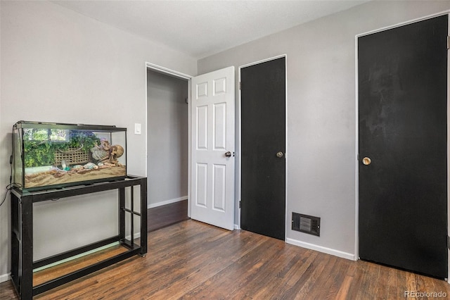 unfurnished bedroom with wood finished floors and baseboards