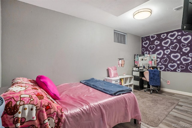 bedroom with wood finished floors, an office area, and baseboards