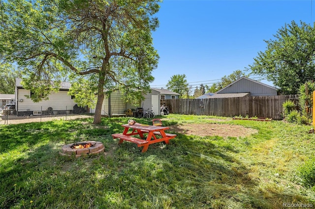 view of yard with a fire pit, a storage shed, and an outbuilding