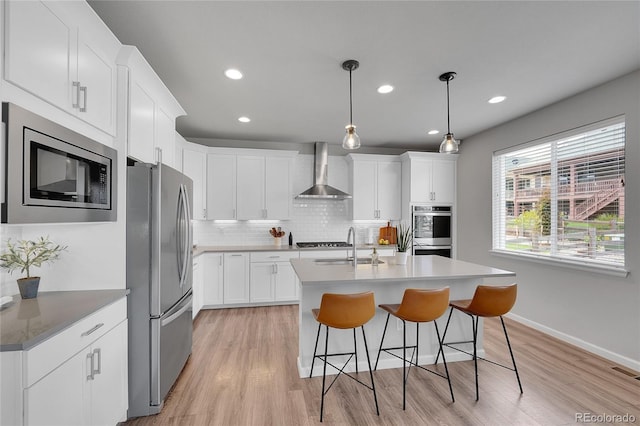 8839 Culebra St, Arvada, CO 80007 - kitchen featuring stainless steel appliances, wall chimney range hood, light wood-type flooring, backsplash, and recessed lighting