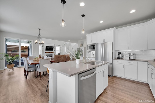 8839 Culebra St, Arvada, CO 80007 - kitchen with appliances with stainless steel finishes, decorative backsplash, light wood-style flooring, a center island with sink, and recessed lighting