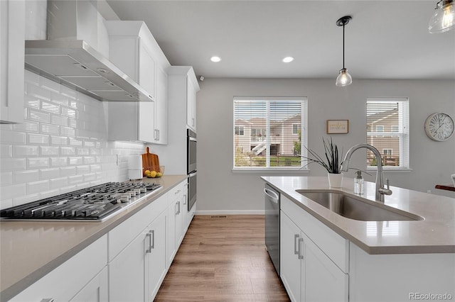 8839 Culebra St, Arvada, CO 80007 - kitchen with wall chimney exhaust hood, appliances with stainless steel finishes, backsplash, wood finished floors, and white cabinets