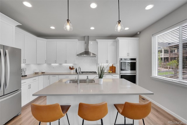 8839 Culebra St, Arvada, CO 80007 - kitchen with stainless steel appliances, wall chimney exhaust hood, backsplash, a kitchen bar, and recessed lighting