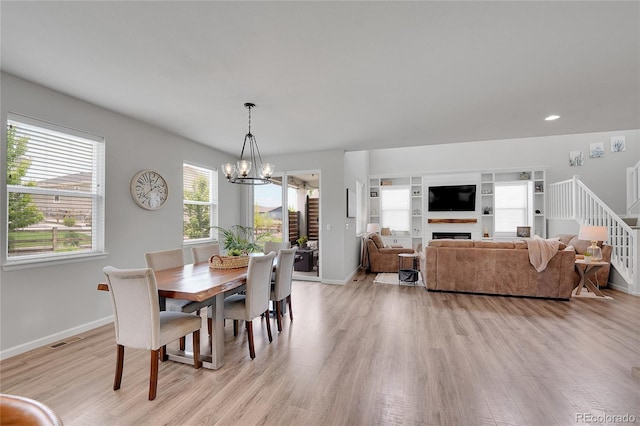 8839 Culebra St, Arvada, CO 80007 - dining area featuring a chandelier, light wood-type flooring, stairs, a fireplace, and recessed lighting