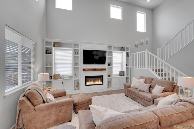 8839 Culebra St, Arvada, CO 80007 - living area with a towering ceiling, stairway, a large fireplace, and wood finished floors