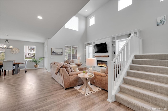 8839 Culebra St, Arvada, CO 80007 - living room with a towering ceiling, light wood finished floors, stairway, a glass covered fireplace, and healthy amount of natural light