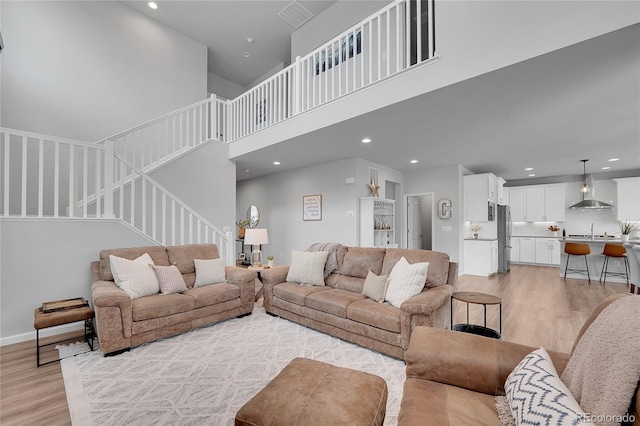8839 Culebra St, Arvada, CO 80007 - living room featuring light wood-style floors, recessed lighting, a high ceiling, and stairs