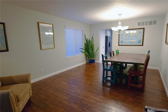 dining space with dark hardwood / wood-style floors and an inviting chandelier