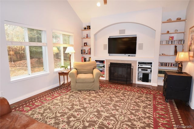 living room featuring hardwood / wood-style floors, built in shelves, and vaulted ceiling