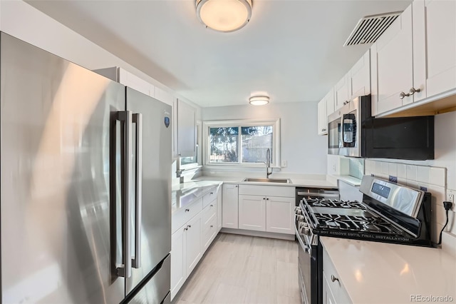 kitchen with backsplash, stainless steel appliances, white cabinetry, and sink