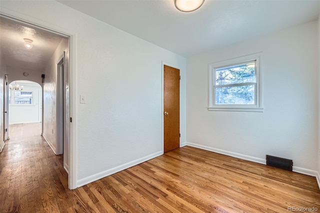 unfurnished room with a chandelier and light hardwood / wood-style floors