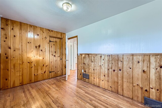 empty room featuring wood walls and light hardwood / wood-style flooring