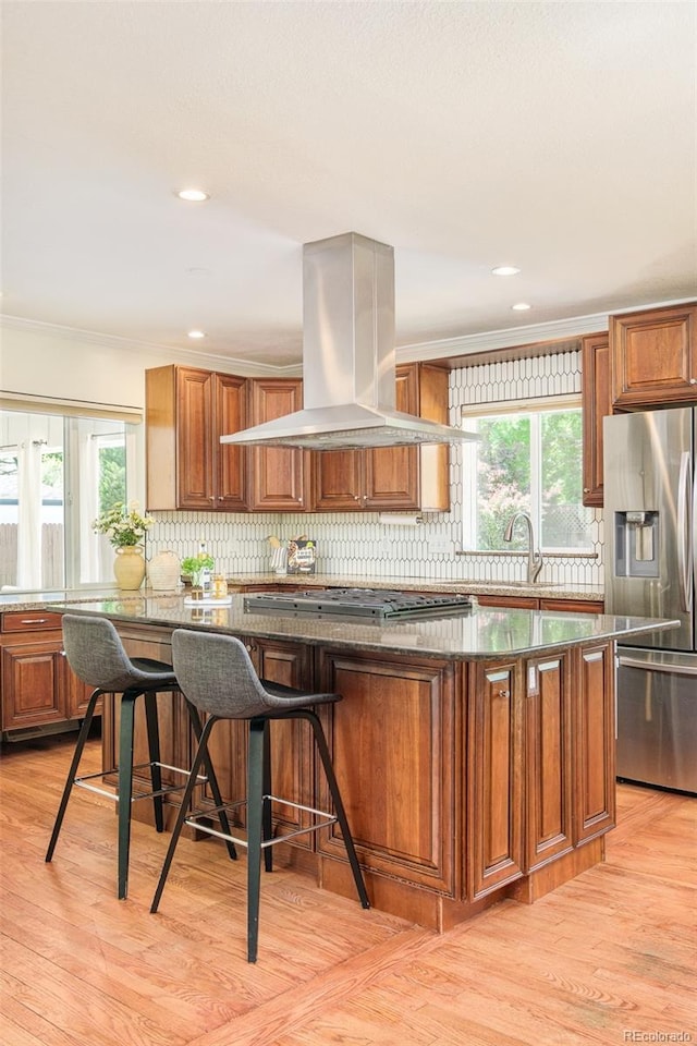 3025 S Norman Ct, Denver, CO 80224 - kitchen featuring island exhaust hood, stainless steel appliances, tasteful backsplash, brown cabinetry, and crown molding