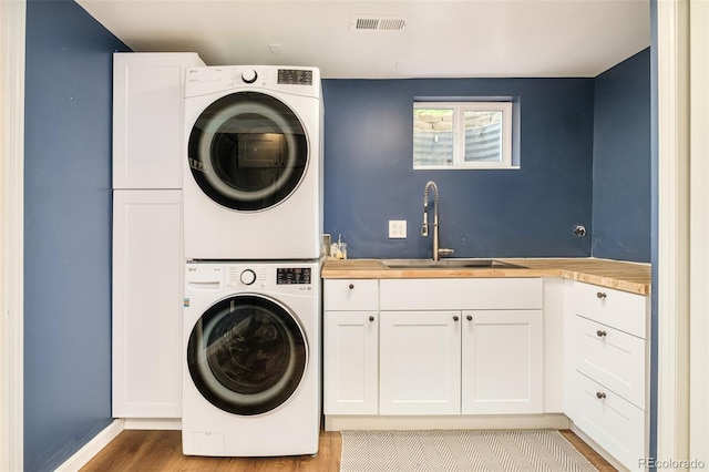 3025 S Norman Ct, Denver, CO 80224 - laundry room with stacked washer and clothes dryer, cabinet space, and wood finished floors