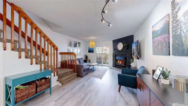 living room featuring a textured ceiling, light hardwood / wood-style floors, and a fireplace