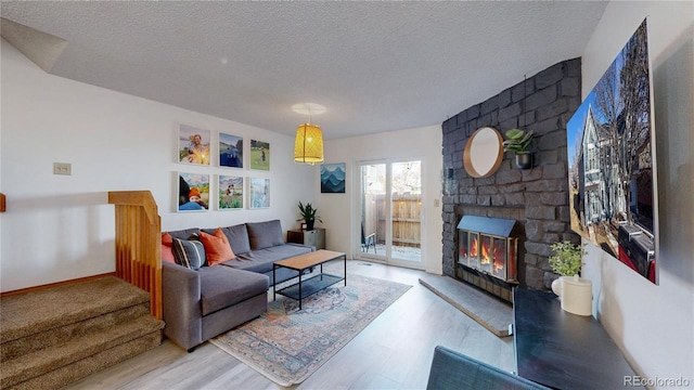 living room featuring light hardwood / wood-style flooring, a large fireplace, and a textured ceiling