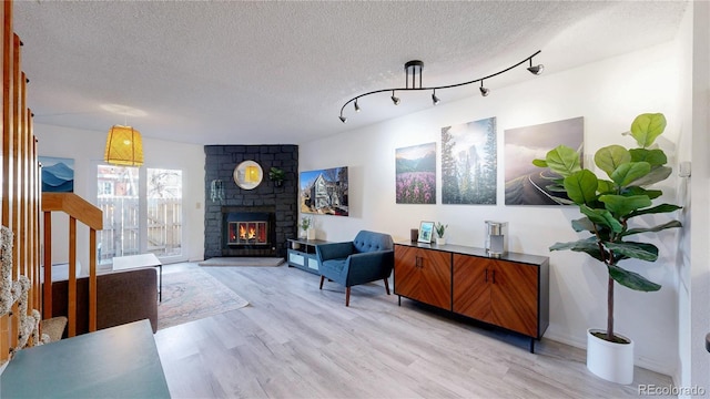 interior space with a fireplace, light hardwood / wood-style floors, rail lighting, and a textured ceiling