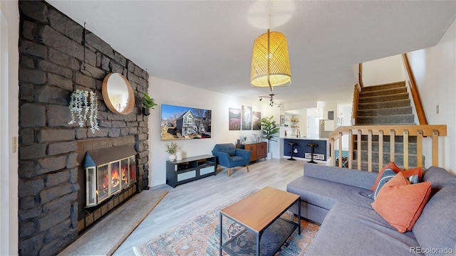 living room featuring a stone fireplace, sink, and hardwood / wood-style floors