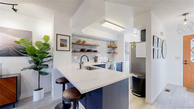 kitchen featuring a breakfast bar, sink, tasteful backsplash, electric range, and kitchen peninsula