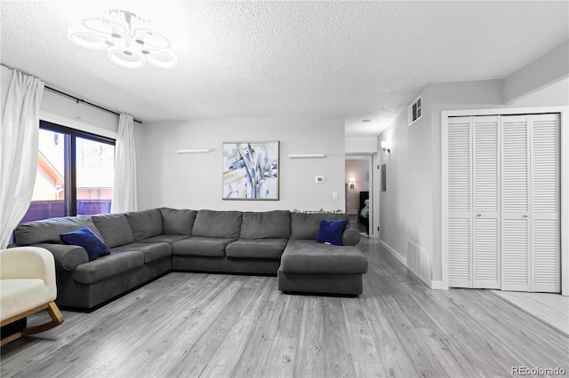 living area featuring visible vents, a textured ceiling, and wood finished floors