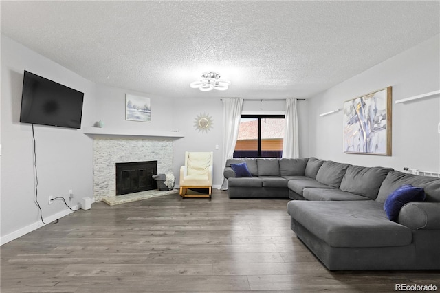 living room featuring a fireplace, a textured ceiling, baseboards, and wood finished floors