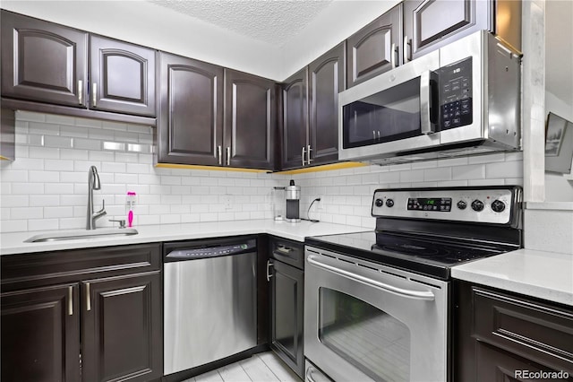 kitchen featuring a sink, tasteful backsplash, appliances with stainless steel finishes, and light countertops