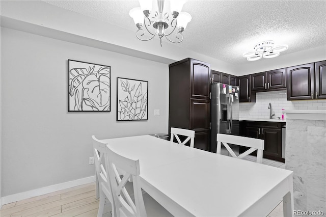 kitchen featuring a notable chandelier, stainless steel fridge, light wood finished floors, and a sink