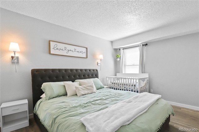 bedroom with a textured ceiling, baseboards, and wood finished floors