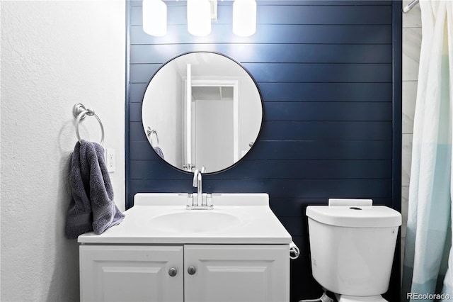 bathroom with vanity, toilet, and a textured wall