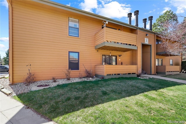 view of front of house featuring a balcony and a front lawn