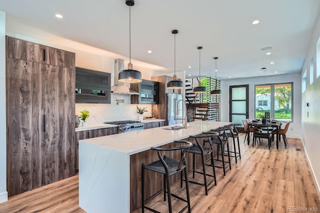 4476 Utica St, Denver, CO 80212 - kitchen featuring wall chimney exhaust hood, high end appliances, decorative backsplash, recessed lighting, and a spacious island