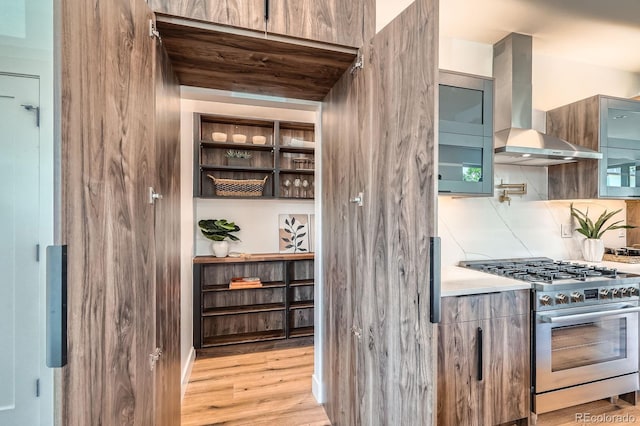 4476 Utica St, Denver, CO 80212 - kitchen with wall chimney range hood, stainless steel gas stove, light wood-style flooring, and glass insert cabinets