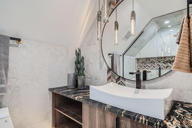 4476 Utica St, Denver, CO 80212 - bathroom featuring tile walls, toilet, vanity, and vaulted ceiling