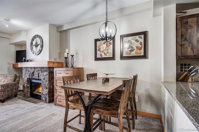 carpeted dining space with a chandelier, baseboard heating, a fireplace, and baseboards