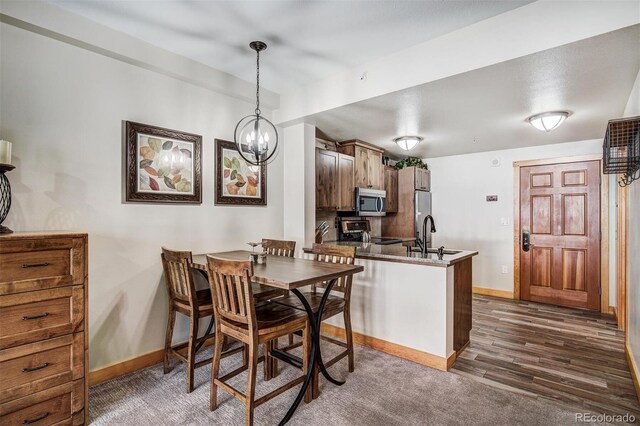 dining space featuring dark wood-style floors, baseboards, and a chandelier